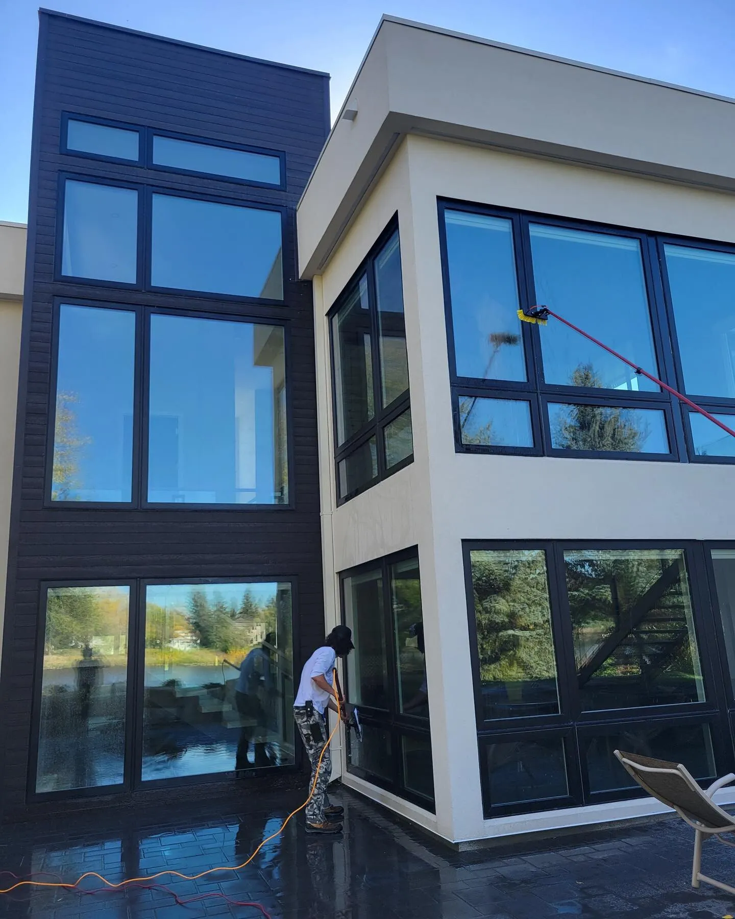 Jet Set technician using a water-fed pole to clean the tall windows of a modern two-storey Winnipeg home